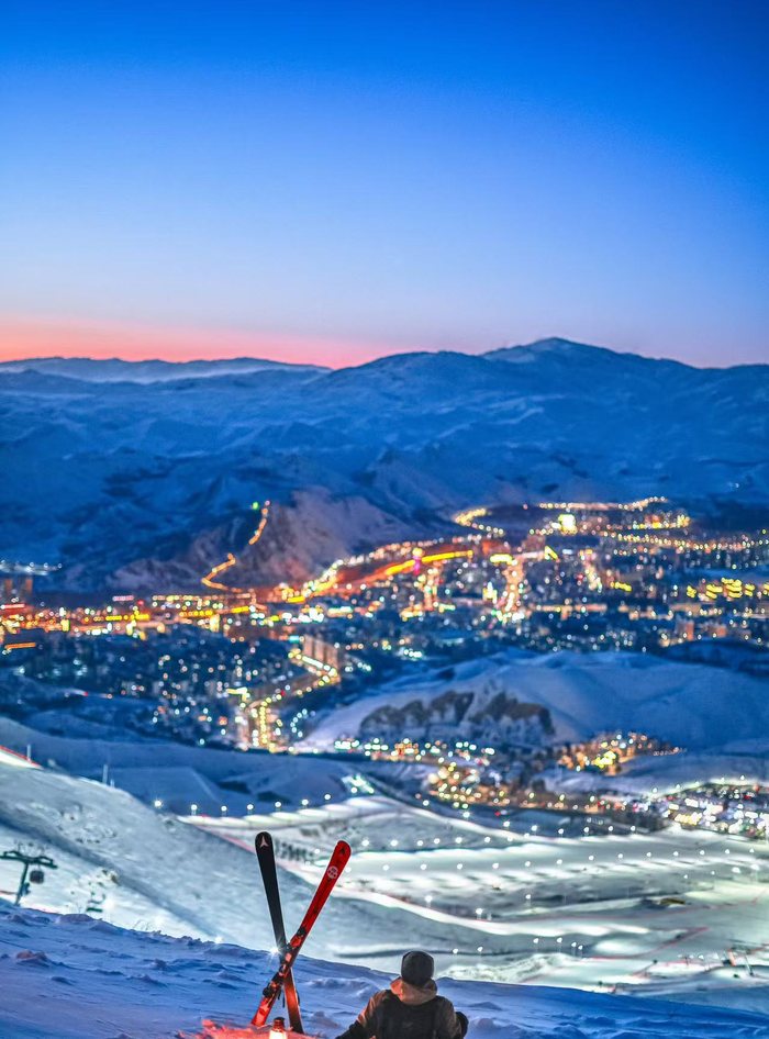 Night skiing above the lit city and ski resort